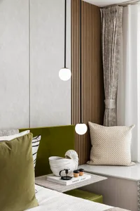 Modern bedroom with green velvet headboard, wooden paneling, and decorative pillows.