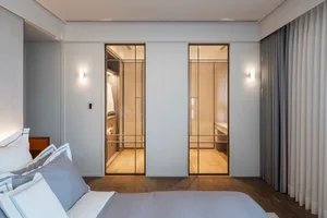 Modern bedroom featuring wooden flooring, fabric bedding, and glass sliding closet doors.
