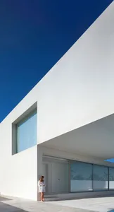 A modern white exterior concrete house with large windows.