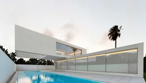 Modern house exterior with large glass windows and a swimming pool.