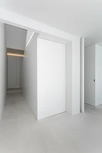 A minimalist white concrete hallway with clean lines and a single light source.