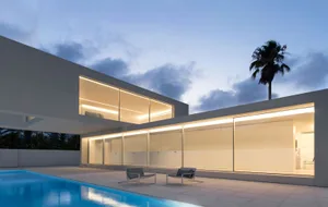 Modern residential house with glass walls at dusk.