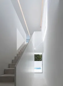 Modern, minimalist staircase and pool area with skylight, showcasing clean lines and natural light.