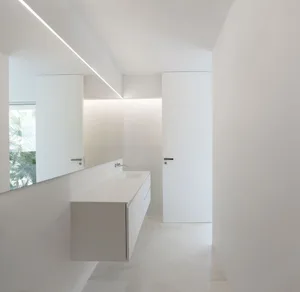Minimalist bathroom with white walls, featuring a floating vanity and a frosted glass door.