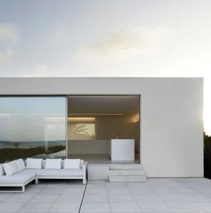 Modern living room with concrete walls, minimalist furniture, and large windows.