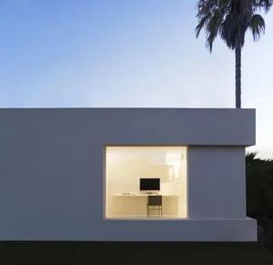 A minimalist office space with a large glass window, white walls, and a clean, modern design.