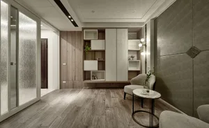 A modern living room with wood flooring, minimalist design, and a small table with a vase and a cup.