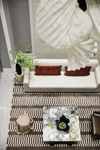 A modern living room featuring a white leather sofa with brown pillows, a marble coffee table, and a patterned rug.