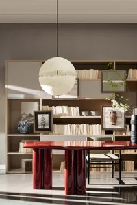 A modern office library with a red lacquered table, books, and hanging light fixture.