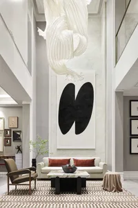 A modern white marble lobby with a white fabric sculpture and black abstract art hanging from the ceiling, white leather couc