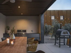 Outdoor kitchen with metal appliances, concrete countertop, and string lights.