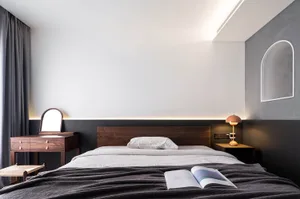A modern minimalist bedroom with soft lighting, a wooden bed frame, and a muted color palette.