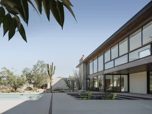 Modern residential backyard patio with large glass windows, concrete surface, and pool renovation.