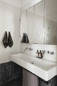 Modern bathroom featuring a white minimalist sink with gray towels and a sleek design.