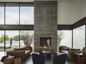 A modern living room with a concrete fireplace and seating area.