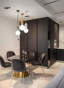 Modern dark-colored kitchen and dining space featuring black marble countertops and dark wood cabinets.