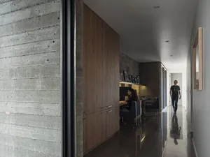 A modern home office with exposed concrete walls and wooden cabinets.