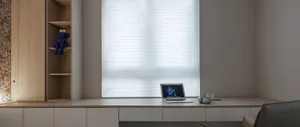 A modern home office setting featuring a wooden desk with a laptop, headphones, and a glass of water.