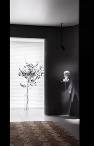 Minimalist home interior featuring a concrete vase with a single plant, a hanging sculpture, and a spotlight.