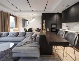 Modern kitchen featuring grey upholstered sofa, grey marble countertops, and black steel kitchen cabinets.