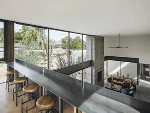Modern living room with metallic countertop bar and floor-to-ceiling windows overlooking desert landscape.