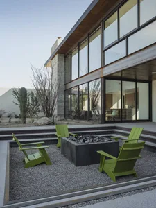 Modern metal patio furniture set with a fire pit in a gravel area.