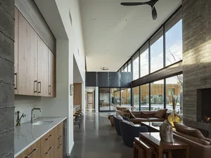 A modern minimalist living room featuring eclectic elements such as concrete, glass, and brick.