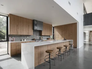 Modern residential kitchen featuring white marble countertops and wooden cabinets.