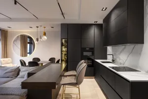 Modern kitchen with black cabinets, marble backsplash, and metal stools.