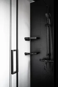 A modern, minimalist bathroom with black and white ceramic tiles, featuring black fixtures and a sleek design.