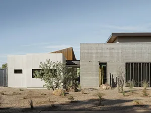 Modern, minimalist house with concrete exterior in a desert setting.
