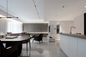 Modern kitchen and living room with white marble surfaces.