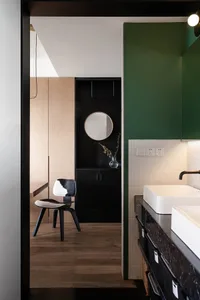 A modern bathroom with green walls, marble countertops, and wooden accents