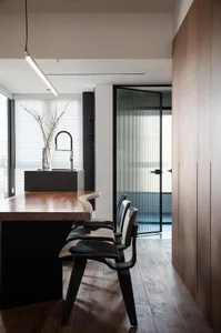 Modern kitchen with wooden counter featuring black and white stools and a sink with a black faucet.