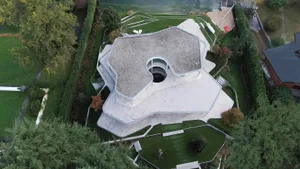 An aerial view of a modern house with a unique shape and concrete exterior.