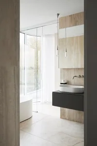 Modern minimalist bathroom with stone surfaces and a white bathtub.