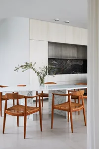 A minimalist dining room with a marble table and wooden chairs.