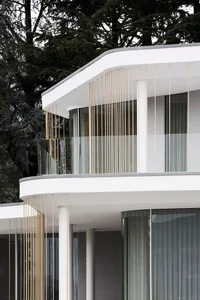 A modern minimalist home exterior featuring glass walls and metal accents.