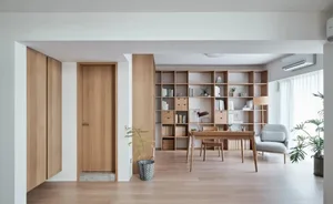 Modern minimalist living room interior with light-colored wooden furniture and shelves.