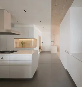Modern minimalist residential kitchen with white cabinets, light hardwood flooring, and a central island.