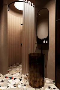Modern minimalist bathroom featuring a white terrazzo floor with black and red accents, a round shower with a white curtain,
