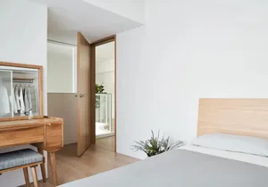 A minimalist bedroom featuring a bed with a wooden headboard and a glass closet door.