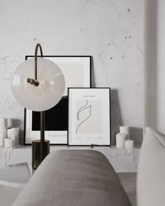 A minimalist living room featuring a bench and a table lamp with candles and framed artworks on the wall.