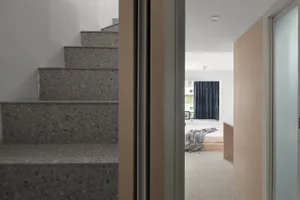A modern bedroom with concrete stairs and a minimalist design.