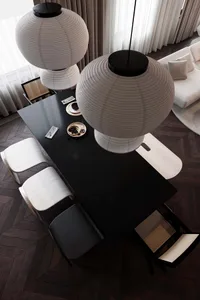 A modern dining room with black glass table, white chairs, and pendant lights.