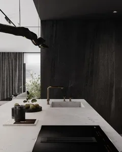 A modern kitchen featuring a white marble countertop, a black stove, and a black faucet with a gold finish.