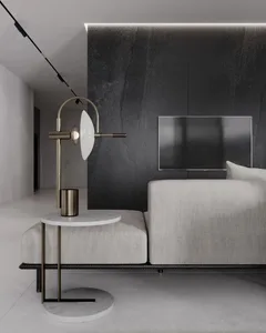Modern living room with a concrete and marble design, featuring a minimalist sofa and side table with a sleek lamp.
