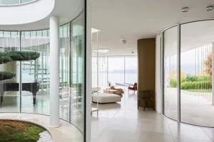 Spacious modern living room with large glass walls overlooking a serene lake