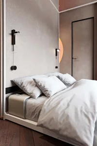 Modern minimalist bedroom with white bed, white linens, and white pillows on a white bed frame with black accents.
