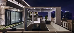 Modern rooftop patio with concrete and glass elements, featuring a lounge area and cityscape view at night.